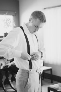 Groom doing up his suspenders