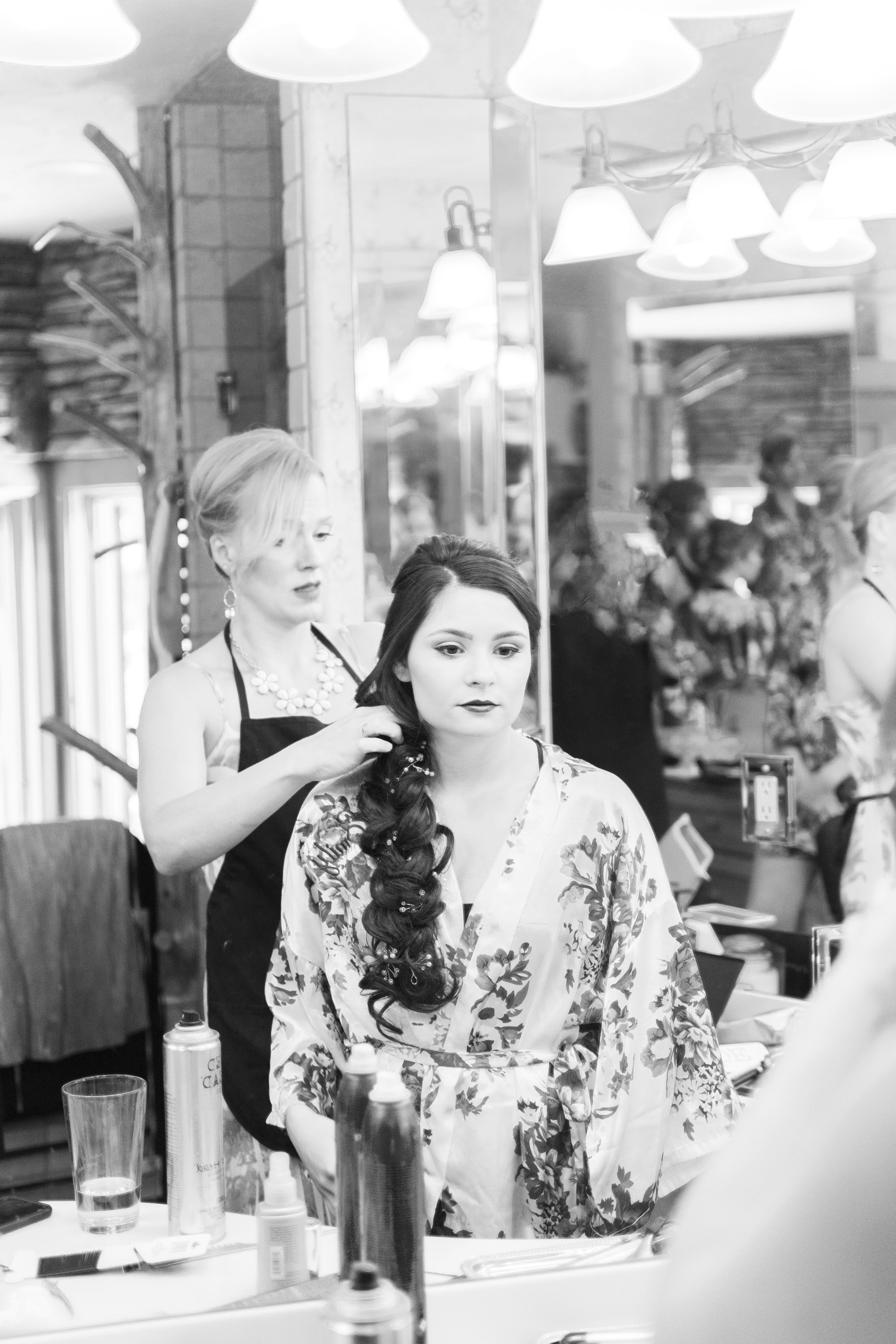 Bride looking into mirror while getting her hair done